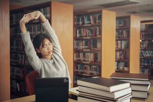 Student girl reading and doing stretch oneself in library of university or colleage. photo