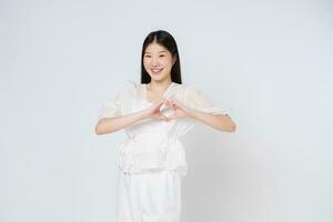 Smilling woman doing a heart shaped gesture with her fingers isolated on whitebackground. Valentine's Day concept. photo