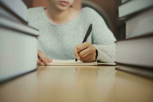 Student preparing for college test, exam, reading book, studying textbook, writing notes, making summary for class report. Learning workplace table, hands with pencil close up photo