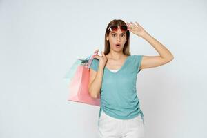 Happy young woman wearing sunglasses and holding  shopping bags isolated on white background. photo