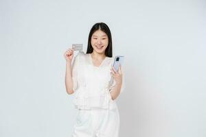 Happy young woman showing credit card while holding mobile phone isolated white background. photo