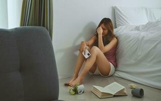 Unhappy woman thinking about problems, sitting on floor in bedroom alone, feeling lonely and sad psychological, suffering from bad relationship, break up or divorce. photo