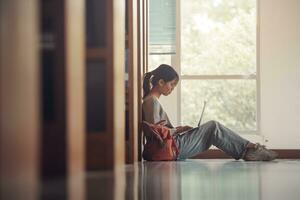 Student girl sitting on floor and using laptop, Writes notes for paper, Essay, Study for class assignment. Diverse group of Students Learning, Studying for Exams. photo