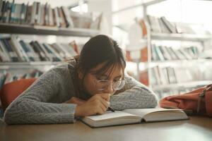 aburrido estudiante niña acostado en libro y leyendo libro, estudiante niña a aburrido lección sensación cansado o deprimido. foto