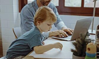 Father working from home office using laptop sit at table with cute little son playing nearly to disturb. photo