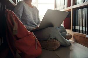 Student girl sitting on floor and using laptop, Writes notes for paper, Essay, Study for class assignment. Diverse group of Students Learning, Studying for Exams. photo