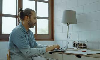 Young worried man using laptop sitting on the desk. photo