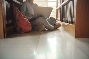 Student girl sitting on floor and using laptop, Writes notes for paper, Essay, Study for class assignment. Diverse group of Students Learning, Studying for Exams. photo