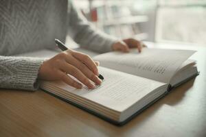 Student preparing for college test, exam, reading book, studying textbook, writing notes, making summary for class report. Learning workplace table, hands with pencil close up photo