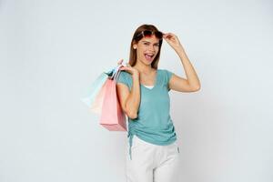 Happy young woman wearing sunglasses and holding  shopping bags isolated on white background. photo