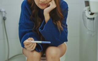 Unstressed woman sitting on toilet and waiting for pregnancy test results. photo