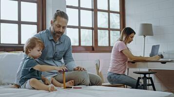 Father and son playing toy while their mother working from home  using laptop sit at table. photo