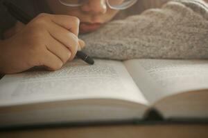 aburrido estudiante niña acostado en libro y leyendo libro, estudiante niña a aburrido lección sensación cansado o deprimido. foto