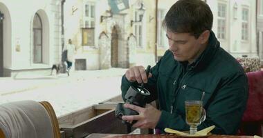 Man cleaning camera lens in outdoor cafe video