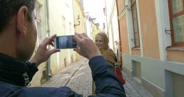 Man making photo of a woman with cell phone video