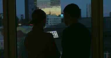 Young people using pad by the window at night video