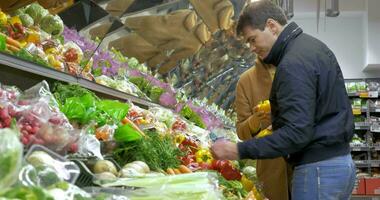 homem e mulher comprando fresco legumes dentro supermercado video