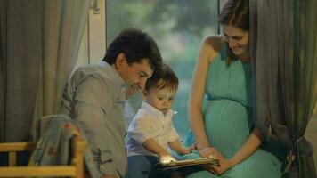 Parents and child playing on touch pad at home video