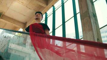 an Asian man standing on a broken escalator with a red cloth wrapped around his body video