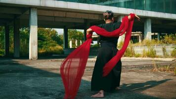 an Asian man running and dancing with a red scarf on his body that flies in the wind in an abandoned building video