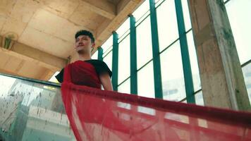 an Asian man standing on a broken escalator with a red cloth wrapped around his body video