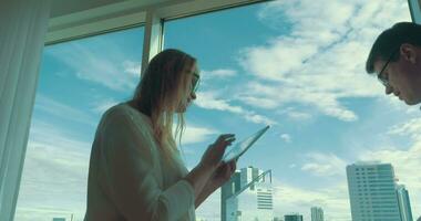 Young people with pad and laptop dancing by the window video