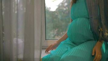 Enceinte femme séance sur rebord de fenêtre et embrassement ventre video