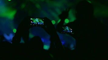 People with mobiles shooting laser show on the concert video
