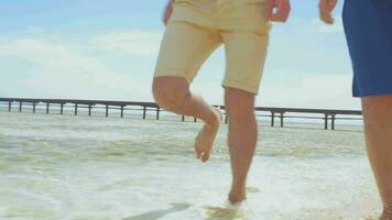 Barefoot couple running in shallow water on the beach video