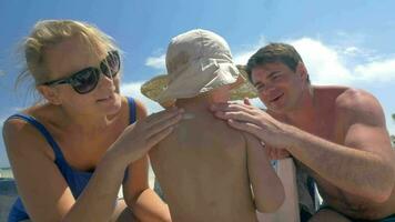 Parents applying suntan lotion on childs skin video