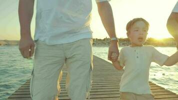 Grandparents with grandchild on the pier at sunset video