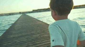 pequeño chico corriendo en el muelle a puesta de sol video