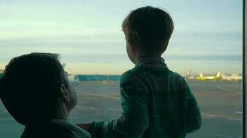 hijo y papá mirando a aeropuerto zona mediante el ventana video