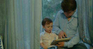 padre e figlio che guardano cartoni animati in tablet video