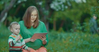 Pregnant mother and son using pad in the park video