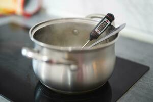 a pan on an electric stove and a thermometer measures the temperature photo