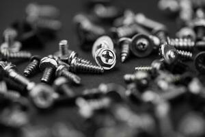 many different screws scattered on a black background photo