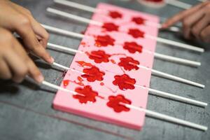 process of making delicious lollipops by pouring them into molds photo