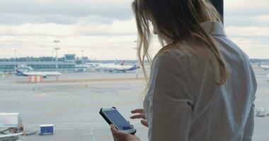 Woman texting on cell and looking at airport area video