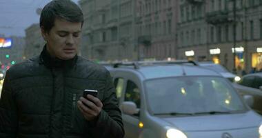 homme avec téléphone portable dans le soir pluvieux ville video