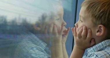 jongen op zoek uit de trein venster met handen Aan de gezicht video