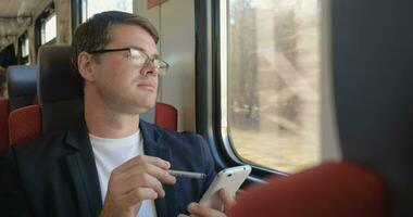 homme avec cellule téléphone profiter vue de le train fenêtre video