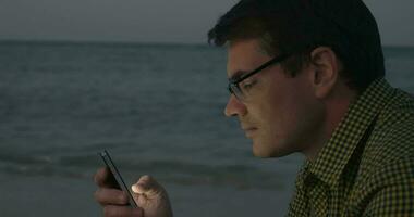 Jeune homme communicant sur cellule par le mer video