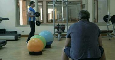 Man exercising with weight disks, his friend having a rest video