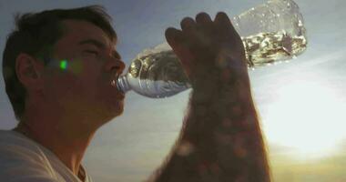 Young man drinking water outdoor at sunset video