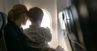 madre e figlio guardare su illuminatore nel aereo video