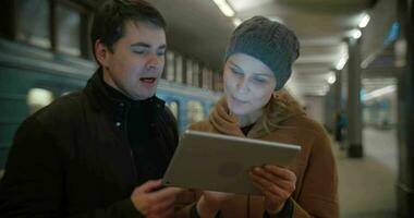 Young people discussing something using pad at metro station video