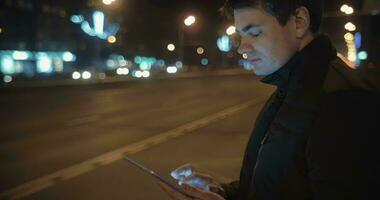 Homme écrivant des lettres en tablet pc en attendant le bus video