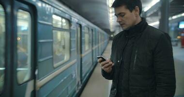 Man typing sms standing on the subway platform video