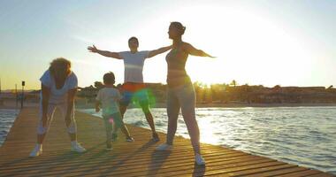 familie oefenen Aan de pier Bij zonsondergang video